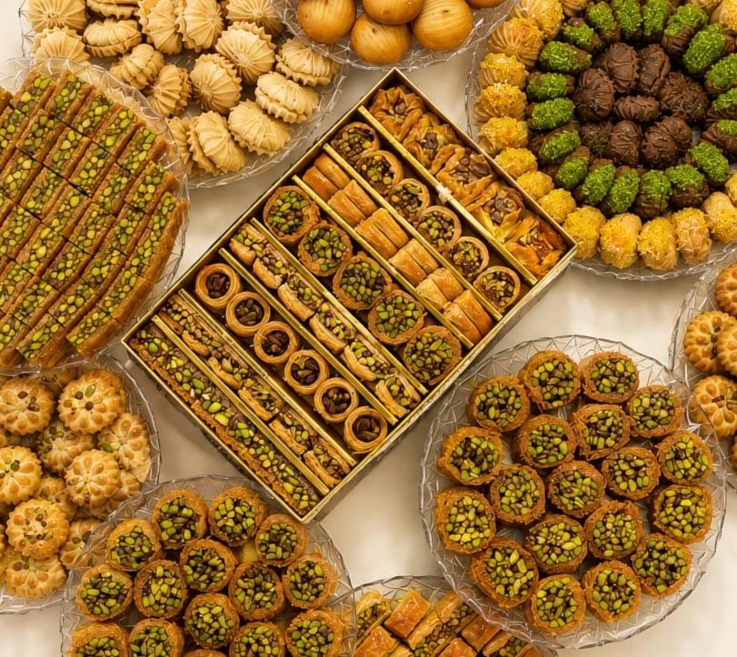 Assorted oriental sweets — baklava, ma'amoul and pistachio pastries on trays